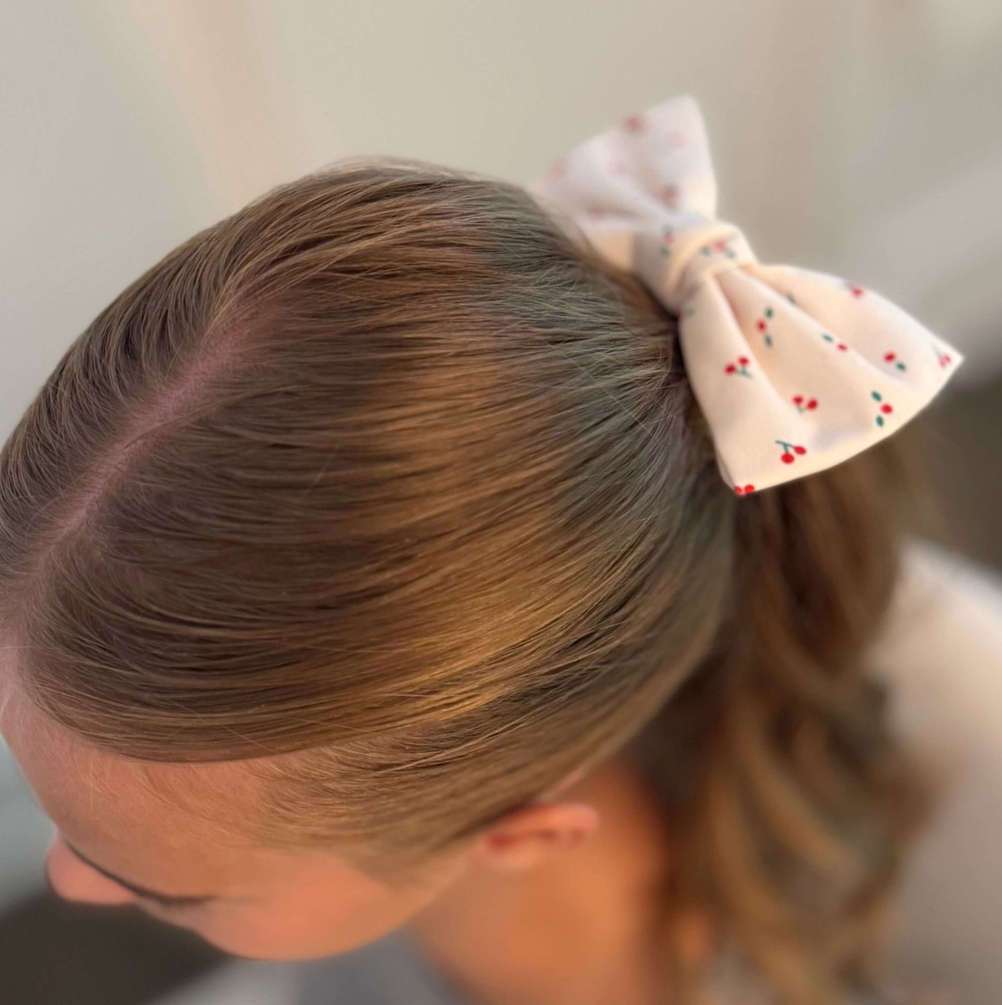 Cherry Lovely Bow Tie Hair Scrunch in a stylish ponytail with a cherry print and bow tie detail.
