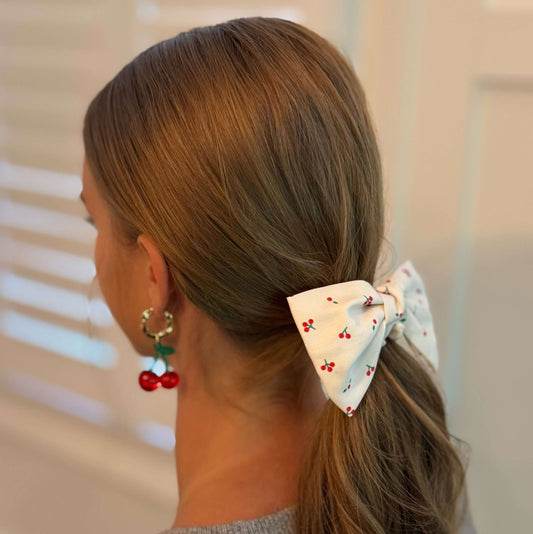 Cherry Lovely Bow Tie Hair Scrunch worn in a ponytail with a playful cherry print and bow tie design.